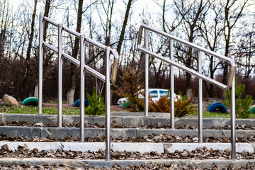 Modern embankment in the Rostov region, small railings and steps of gray concrete. Metal shiny stainless steel handles. The construction on nature, among trees in the usual clear day