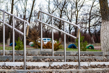 Modern embankment in the Rostov region, small railings and steps of gray concrete. Metal shiny stainless steel handles. The construction on nature, among trees in the usual clear day