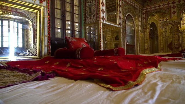 Chandra Mahal,  Jaipur City Palace, Rajasthan, India. Handheld. The room is filled with rich linens, glass and tilework covering the extent of the room. 