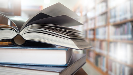 Blurred image, open book page on wood desk in the library room for business and  education...