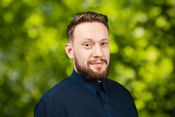 Portrait of handsome adult man on green bokeh background. Caucasian man with beard smiling. Businessman.