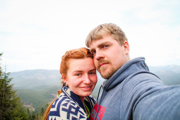 Fototapeta premium Couple of lovers guy and girl in the mountains kiss and hug. Traveling couple. Love in the Carpathians