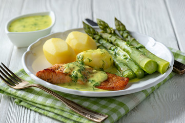 Roasted salmon with boiled potatoes and asparagus in creamy dill sauce.
