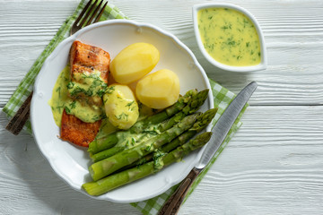 Roasted salmon with boiled potatoes and asparagus in creamy dill sauce.