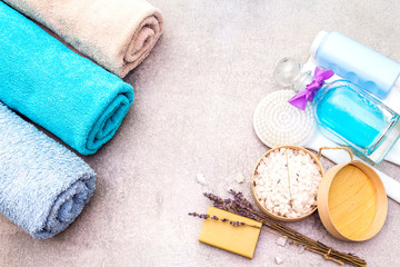 Spa concept, natural ingredients. Bath towels, sea salt with lavender, natural olive soap, shower gel, brush. On a stone background, top view