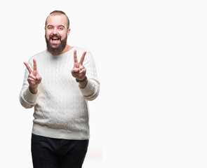 Young caucasian hipster man wearing winter sweater over isolated background smiling looking to the camera showing fingers doing victory sign. Number two.