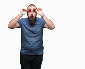 Fototapeta premium Young caucasian hipster man wearing sunglasses over isolated background afraid and shocked with surprise expression, fear and excited face.
