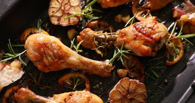 Grilled chicken. Grilled chicken legs, drumsticks with addition  garlic, lemon and fresh rosemary on grill plate, top view. Grill food