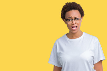 Beautiful young african american woman wearing glasses over isolated background In shock face, looking skeptical and sarcastic, surprised with open mouth