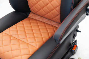 A view of a part of the interior of the car seat from leather of black and beige color, stitched...