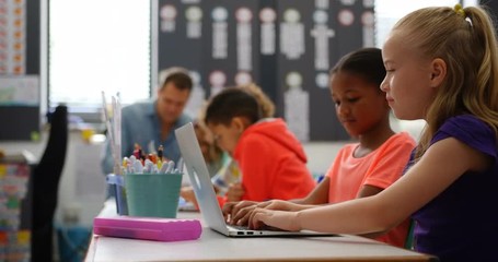 Side view of Mixed-race schoolgirls studying on laptop in the classroom 4k - Powered by Adobe