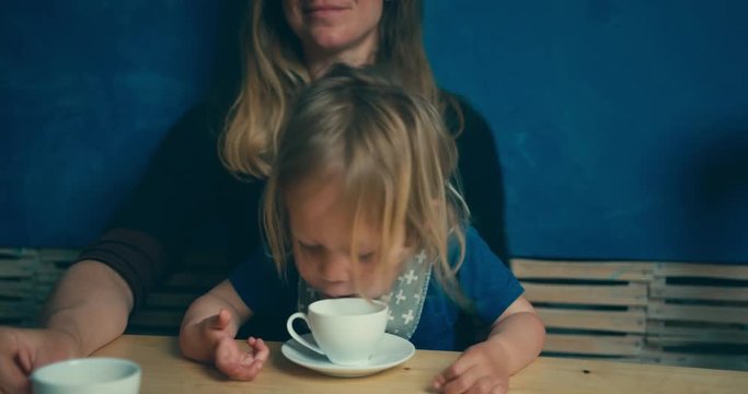 Little toddler drinking coffee with his mother