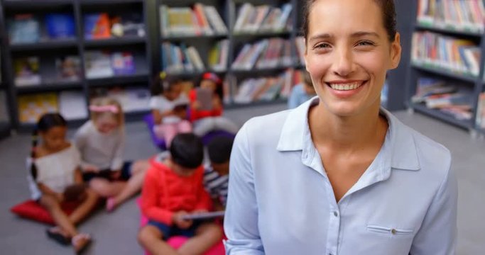 Front view of happy Caucasian female teacher standing in the school library 4k
