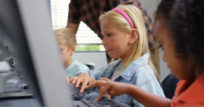 Side view of Caucasian schoolgirl studying on personal computer male teacher teaching schoolkids in 