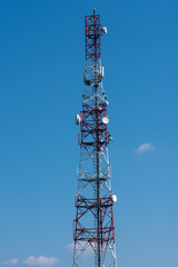 Communication tower on the green field against clean blue sky