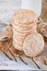 Round almond cookies on the wooden board and a bottle of milk in the background