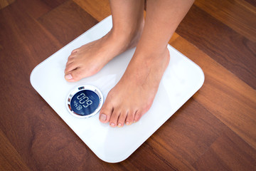 Woman bare feet standing on a digital scale with body fat analyzer that uses bioelectrical impedance (BIA) to gauge the amount of fat in your body
