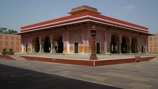 Visitors explore the courtyard at the City Palace. Red and pink limestone. Handheld. Jaipur, Rajasthan, India.  The structure was built in 1799 by Maharaja Sawai Pratap Singh