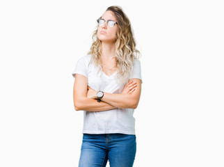 Beautiful young blonde woman wearing glasses over isolated background skeptic and nervous, disapproving expression on face with crossed arms. Negative person.