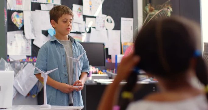 Front view of Caucasian schoolboy explaining about windmill model in the classroom 4k