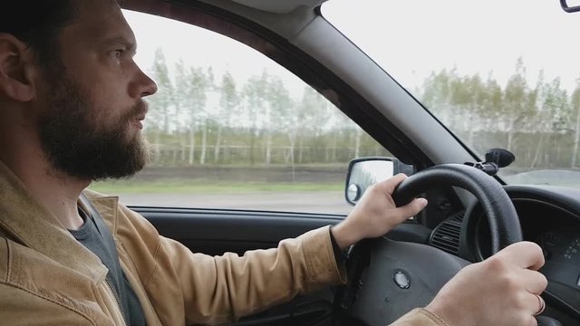 A man gets into the car and turns on the navigator on the smartphone