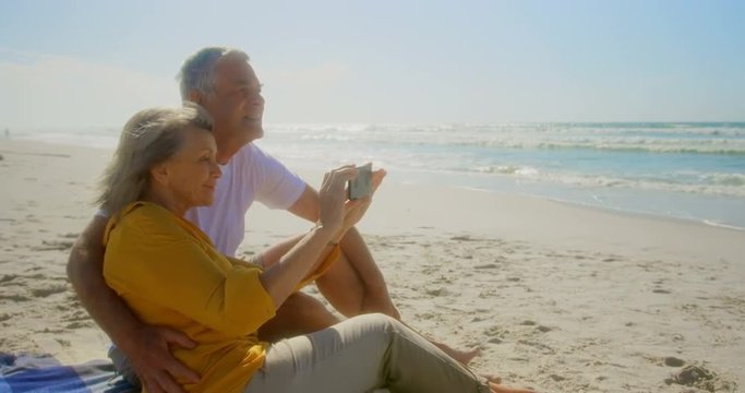 Side view of active senior Caucasian couple clicking photos on the beach 4k