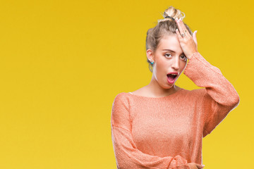 Beautiful young blonde woman over isolated background surprised with hand on head for mistake,...