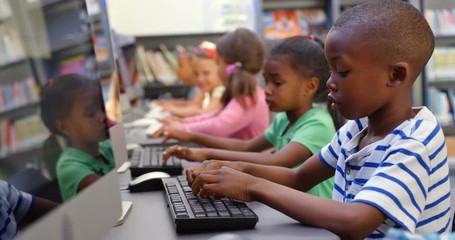 Side view of mixed-race schoolkids studying on computer in the classroom 4k - Powered by Adobe