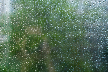 Drops of rain on glass with green background texture