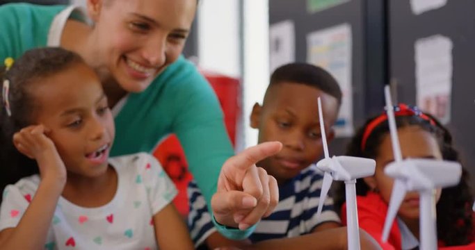 Front view of Caucasian female teacher teaching student about windmill in the classroom 4k