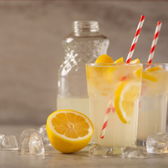 two glasses of lemonade with lemons and lime and straw, a bottle with a cool drink and summer mood, with ice, freshness in hot summer