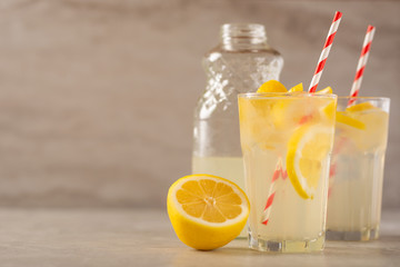 two glasses of lemonade with lemons and lime and straw, a bottle with a cool drink and summer mood, with ice, freshness in hot summer