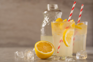 two glasses of lemonade with lemons and lime and straw, a bottle with a cool drink and summer mood, with ice, freshness in hot summer