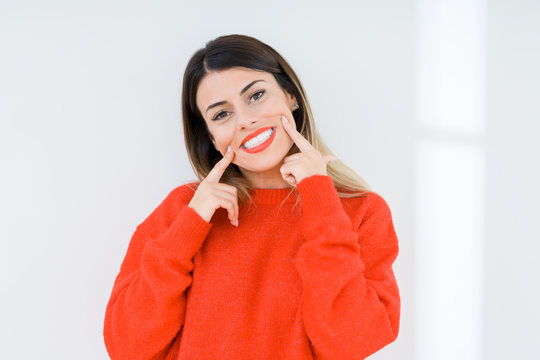 Young woman wearing casual red sweater over isolated background Smiling with open mouth, fingers pointing and forcing cheerful smile