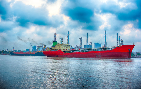 Red cargo ship in the river with Clouds, Blue sky and Oil refinery background - Image