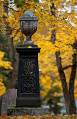 An old memorial on an ancient graveyard with beautiful yellow maple trees in autumn