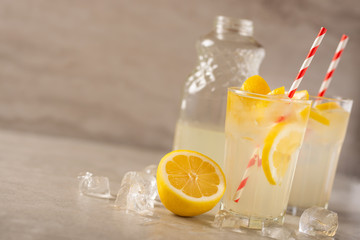 two glasses of lemonade with lemons and lime and straw, a bottle with a cool drink and summer mood, with ice, freshness in hot summer