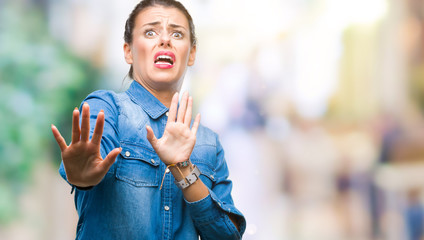 Young beautiful woman over isolated background afraid and terrified with fear expression stop gesture with hands, shouting in shock. Panic concept.