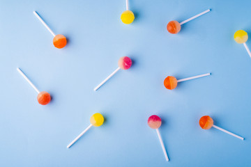 Scattered lollipop candies on blue background top view