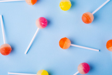 Scattered lollipop candies on blue background top view