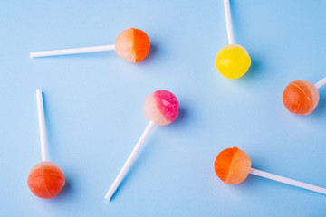 Scattered lollipop candies on blue background top view