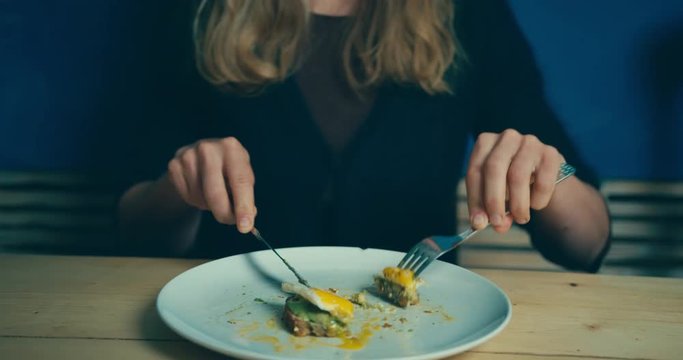 Young woman eating egg for breakfast