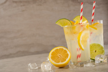 two glass of lemonade with lemons and lime and straw, on a dark background, with space, a cool drink and summer mood