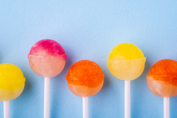 Lollipop candies in row on blue background top view