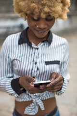 Young Black Stylish Woman Walking On The City Street  With A Smartphone