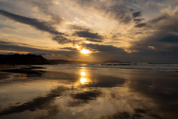 Fototapeta premium sunset on the beach of Atxabiribil, Sopelana, vizcaya. The sun is reflected on the seashore
