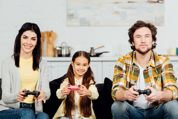 cute and happy kid playing video game with parents at home