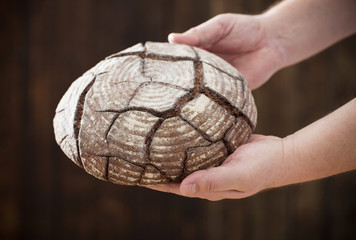 hands with bread on wooden background