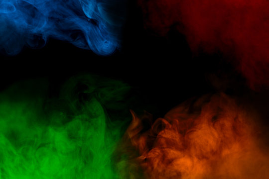 Four Fantastic Multicolored Clouds Of Cigarette Vapor Blue Green Orange And Red Against A Dark Background