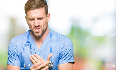 Handsome doctor man wearing medical uniform over isolated background Suffering pain on hands and fingers, arthritis inflammation